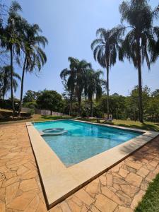 a swimming pool with palm trees in the background at Chácara Minas Garten in Jundiaí