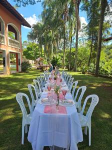 a long table with white chairs and wine glasses at Chácara Minas Garten in Jundiaí