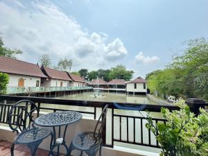 a balcony with tables and chairs and a view of a river at Pludhaya Resort & Spa in Phra Nakhon Si Ayutthaya
