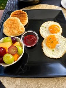 a black tray with a plate of food with eggs and fruit at Suite Matrimonial con Piscina Desayuno Ambiente Exclusivo in Machala +7 photos