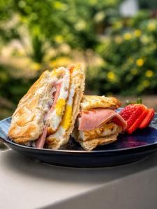 a sandwich and a strawberry on a blue plate at Suite Matrimonial con Piscina Desayuno Ambiente Exclusivo in Machala
