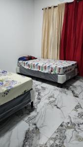 two beds sitting in a room with marble floors at Casa Lujosa in Choluteca