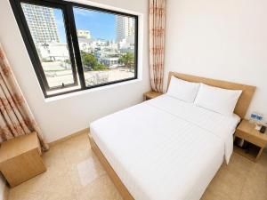 a bedroom with a white bed and a window at Salux Hotel in Danang