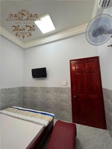 a room with a bed and a red door and a fan at Nhà nghỉ Thanh Thư 2 in Vị Thanh