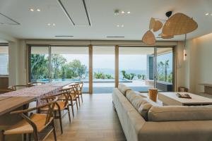 a living room with a long couch and tables and chairs at SHIMASTREAM house in Shodoshima