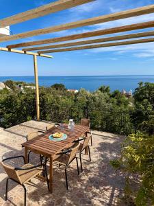 a wooden table and chairs on a patio with the ocean at Ftero Traditional Retreat in Manganítis
