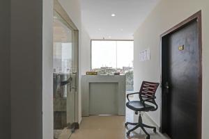 a black chair sitting in a hallway with a window at Hotel O Rudra Palace Near Phoenix United Lucknow in Alambagh