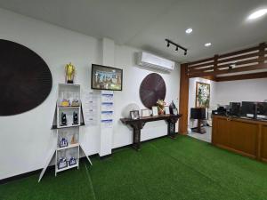 a room with a green carpet and a desk with a table at NJ INTHAI Hotel in Sathani Chiang Rak
