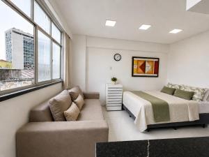 a bedroom with a bed and a couch and a window at Studio no Centro com Wi-Fi in Manaus