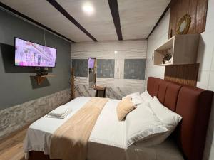 a bedroom with a large bed and a flat screen tv at Hospedaje Salento in Salento