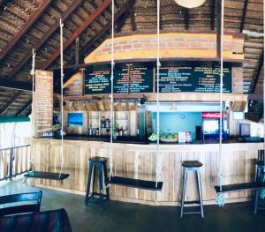 a bar in a restaurant with two stools and signs at Marakolliya Beach Resort in Tangalle