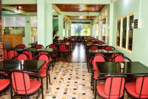 a room filled with tables and red chairs at hotel raj palace in Londa