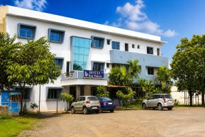 a white building with two cars parked in front of it at hotel raj palace in Londa