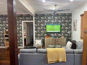 a living room with a couch and a tv on a wall at The Cooby in Spearwood