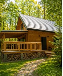 a large wooden cabin with a porch and a walkway at W Sam Las Komfortowy domek na skraju lasu z gorącą balia in Orzyny