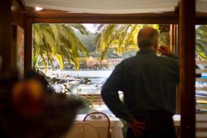 a man looking out of a window at a beach at Hotel Della Baia in Portovenere