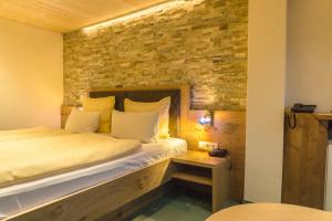 una camera da letto con un letto con un muro di mattoni di Wanderhotel Grüner Baum a Bach