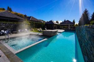 a swimming pool with blue water in a yard at Alpine Cardrona by Aotearoa Escapes in Cardrona