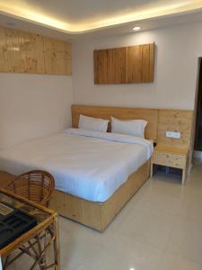 a bedroom with a large bed with white sheets at Bhagirathi Homestay in Joshīmath