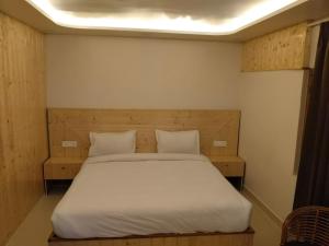 a bedroom with a large bed with white sheets and pillows at Bhagirathi Homestay in Joshīmath