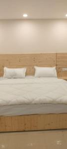 a large bed with white sheets and pillows on it at Bhagirathi Homestay in Joshīmath