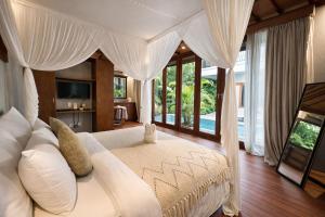 a bedroom with a white bed with a canopy at ZIN Berawa Villas & Bungalows in Canggu