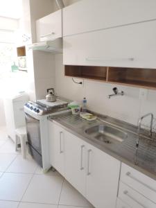 cocina blanca con fregadero y fogones en Apartamento Residencial Ghanem, en Florianópolis