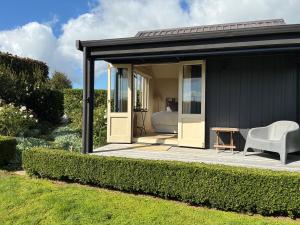 a black shed with a white chair and a bed at Tswalu in Raglan