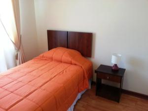 una camera da letto con un letto con una coperta arancione e un tavolo di Hospedaje Rancagua - Centro - Hermoso Departamento a Rancagua