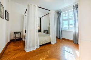 ein Schlafzimmer mit einem Bett mit Vorhängen und einem Holzboden in der Unterkunft Fürstlich Wohnen am Circus über den Dächern von Putbus in Putbus