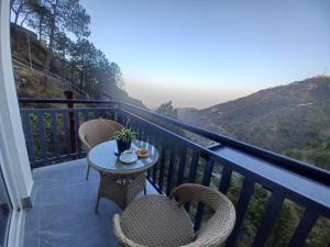 a table and chairs on a balcony with a view at Pahadi Basera Kasauli in Kasauli +7 photos