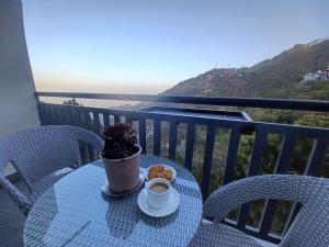 a table with a cup of coffee and cookies on a balcony at Pahadi Basera Kasauli in Kasauli