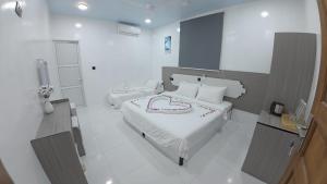 a bedroom with two beds with white sheets and red writing at Skyinn omadhoo in Omadhoo