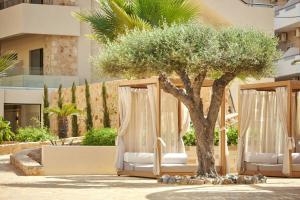 a couple of beds with a tree in front of a building at Alai Crete, a Tribute Portfolio Resort in Stalís