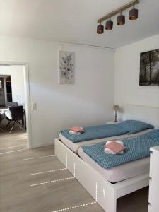 two beds in a white room with a desk at Ferienwohnung Lange in Brilon