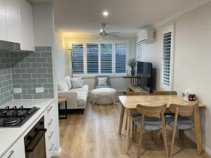 a kitchen and living room with a table and a couch at Chay's Guest House in Coffs Harbour