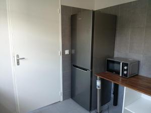 a kitchen with a refrigerator and a microwave on a table at App F4 Kone centre RDC Tel 7O 55 O8 in Koné