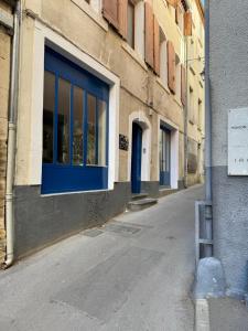an empty street with a blue door on a building at Studio climatisé in Narbonne