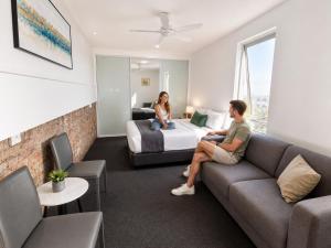 a man and woman sitting on a couch in a hotel room at London Gate Backpackers Hostel in Sydney