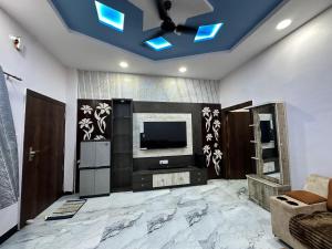 a living room with a tv and a ceiling with blue lights at Mitanvi the heaven in Ujjain