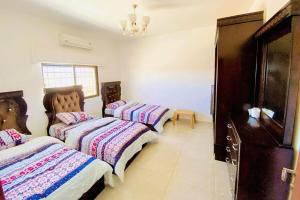 a bedroom with three beds and a dresser at Al Maha Farm in Jerash
