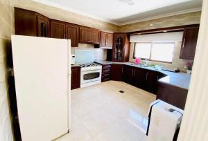 a kitchen with wooden cabinets and a white refrigerator at Al Maha Farm in Jerash