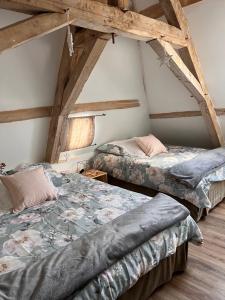 two beds in a room with wooden ceilings at Bblodges Loches Beauval in Saint-Hippolyte