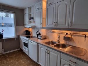 a kitchen with white cabinets and a sink and a window at Villa Mio in Vidsel