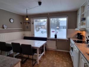 a kitchen with a table and chairs and a kitchen with snow outside at Villa Mio in Vidsel