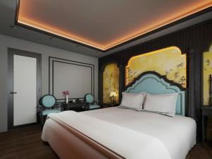 a bedroom with a large white bed with a painting on the wall at Villa Victoria Me Tri in Hanoi