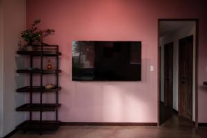 a living room with a tv on a pink wall at bamboo宮古島 in Miyako-jima