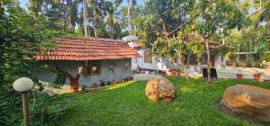 a house with a large rock in the yard at Johny's Villa, Homestay, Wayanad in Pulpally