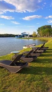 a row of tables and benches next to a lake at Relax II. Vendégház in Dunapataj