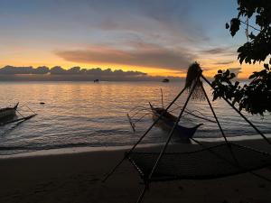 a hammock on the beach with a sunset in the background at Ālon in Linukso